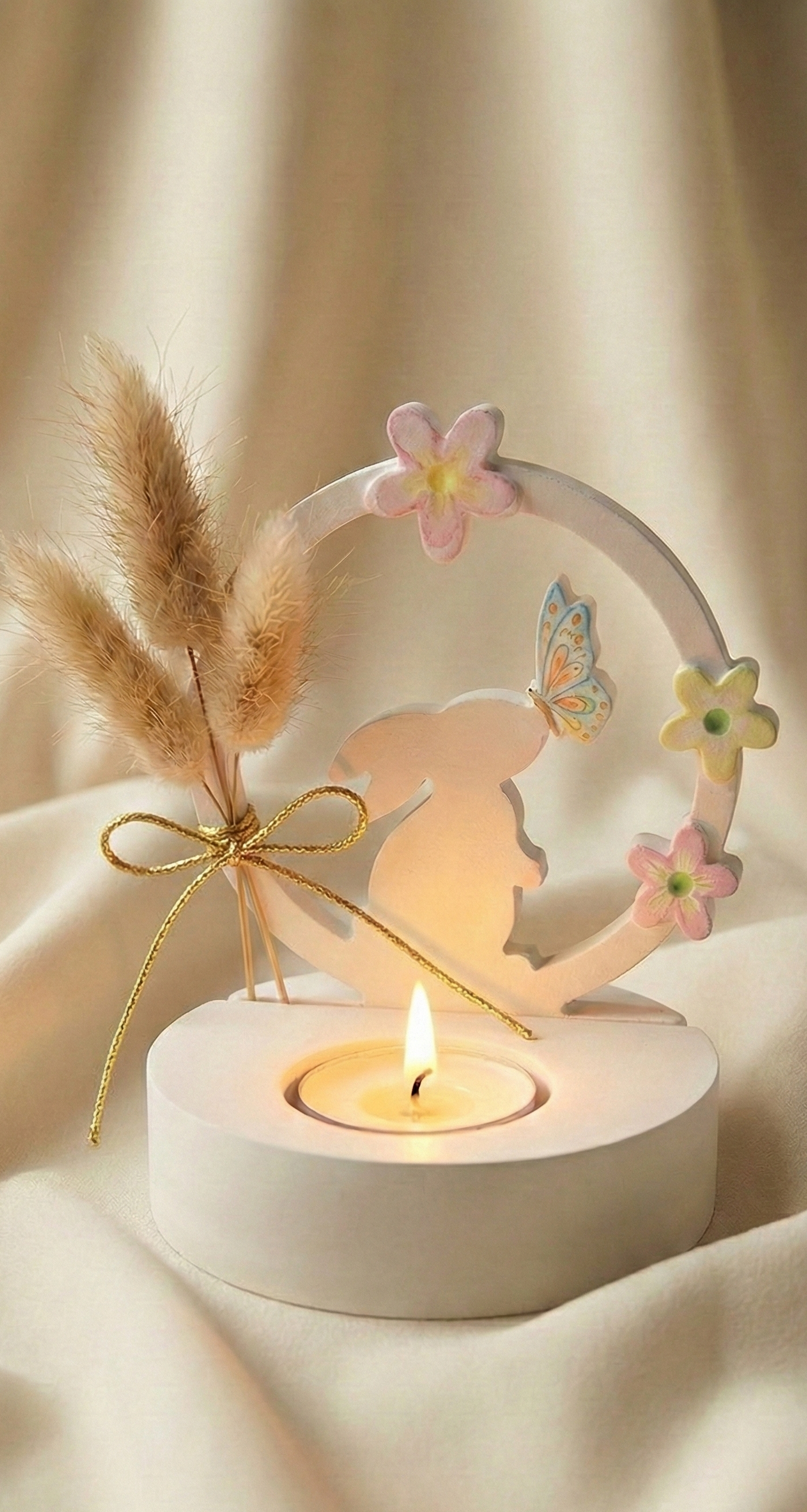 Decorative candle holder with fairy silhouette, flowers, and pampas grass on a soft beige background.
